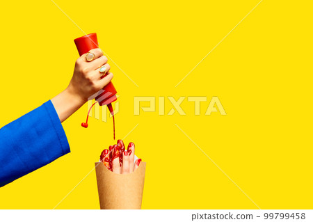 Pouring ketchup. Female fingers instead of fries into packaging against yellow studio background. Surrealism and creativity. Food pop art photography. Pouring ketchup. Female fingers instead of fries into packaging against yellow studio background. Surrealism and creativity. Food pop art photography. 99799458