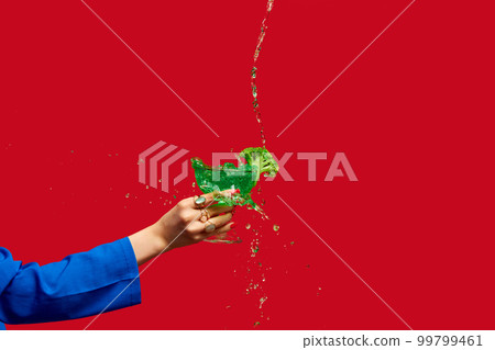 Female hand holding broccoli inside cocktail against red studio background. Healthy eating. Food pop art photography. Female hand holding broccoli inside cocktail against red studio background. Healthy eating. Food pop art photography. 99799461