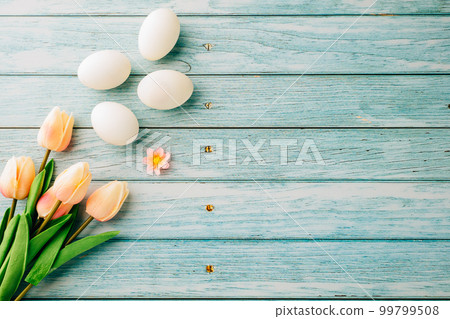 Happy Easter Day Concept. Top view of holiday banner background design white easter eggs and spring tulip flowers on blue wooden background with empty copy space, celebration greeting card Happy Easter Day Concept. Top view of holiday banner background design white easter eggs and spring tulip flowers on blue wooden background with empty copy space, celebration greeting card 99799508