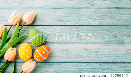 Happy Easter Day Concept. Flat lay holiday banner background web design white colorful easter eggs painted with tulips flowers on blue wood background with empty copy space, overhead, template Happy Easter Day Concept. Flat lay holiday banner background web design white colorful easter eggs painted with tulips flowers on blue wood background with empty copy space, overhead, template 99799545