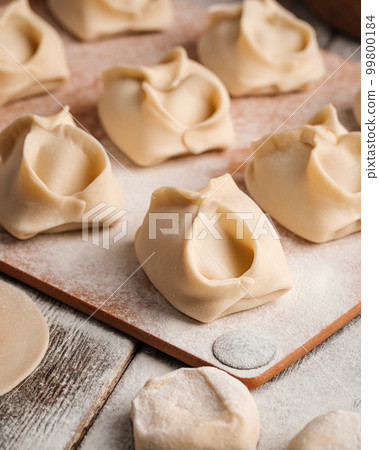 Semi finished manti dumplings on board with flour 99800184