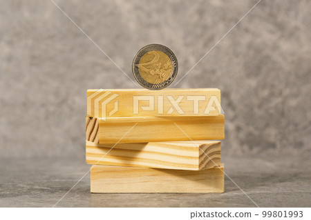Two Euros coin balancing on a wooden blocks tower Two Euros coin balancing on a wooden blocks tower 99801993