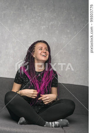 Laughing emotional young woman with violet dreadlocks on her head. Portrait of happy woman. Vertical frame. 99803776