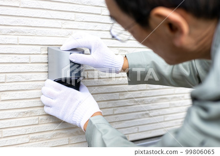 A male worker working on an outdoor outlet for a detached house 99806065