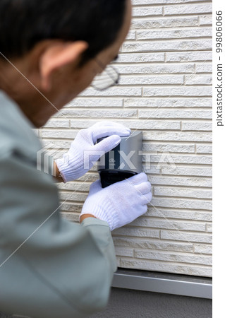 A male worker working on an outdoor outlet for a detached house 99806066