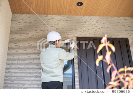 About to install a security camera at the entrance of a detached house About to install a security camera at the entrance of a detached house 99806626