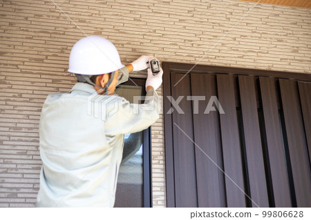 About to install a security camera at the entrance of a detached house About to install a security camera at the entrance of a detached house 99806628