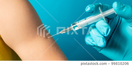 The doctor or nurse injects a syringe to a small child intramuscularly on a blue background. Tuberculosis vaccination, BCG vaccine 99810206