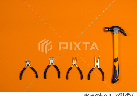 Clippers, pliers, tongs, rounds and hammer on a orange background. Construction tools with a place for copyspace text. Repairing, building materials store 99810968