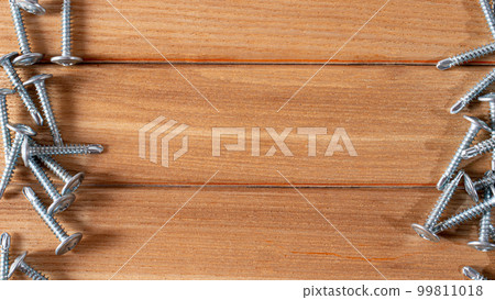 Self-cutters on a wood brown background banner with space for text. Construction tools, self-tapping screws for fastening. Black screw hardware. Self-cutters on a wood brown background banner with space for text. Construction tools, self-tapping screws for fastening. Black screw hardware. 99811018