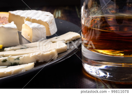 Whiskey in a glass and an appetizer for whiskey blue cheese and Camembert cheese. Appetizer for alcohol, dear spirits. Whiskey in a glass and an appetizer for whiskey blue cheese and Camembert cheese. Appetizer for alcohol, dear spirits. 99811078