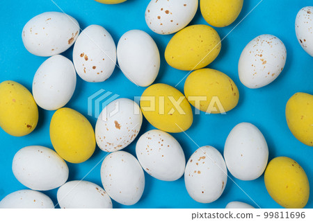White and yellow Easter chocolate quail eggs on a blue background. White and yellow Easter chocolate quail eggs on a blue background. 99811696
