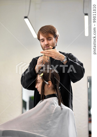 Professional male hairdresser cutting female hair in salon Professional male hairdresser cutting female hair in salon 99811810