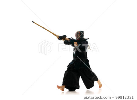 Man, professional kendo athlete in motion, in uniform training with bamboo sword, shinai against white studio background Man, professional kendo athlete in motion, in uniform training with bamboo sword, shinai against white studio background 99812351