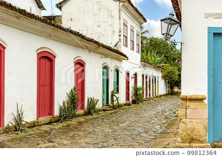 Street with cobblestone pavement and facades of old colonial houses 99812364