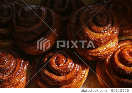 Freshly baked homemade Cinnamon rolls or Cinnamon buns on baking paper Freshly baked homemade Cinnamon rolls or Cinnamon buns on baking paper 99812926