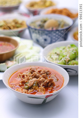 Panaeng Curry with Pork.Sliced M in red curry paste and coconut milk in a bowl on the set of group plates Thai food. Top view. Panaeng Curry with Pork.Sliced M in red curry paste and coconut milk in a bowl on the set of group plates Thai food. Top view. 99813391