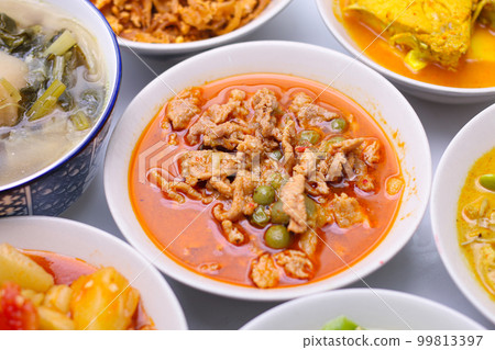 Panaeng Curry with Pork.Sliced M in red curry paste and coconut milk in a bowl on the set of group plates Thai food. Top view. Panaeng Curry with Pork.Sliced M in red curry paste and coconut milk in a bowl on the set of group plates Thai food. Top view. 99813397