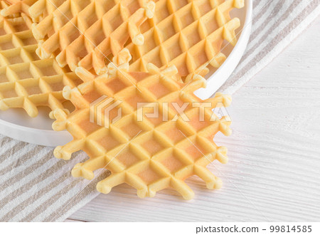 Ferratelle or pizzelle a traditional dessert or cookies from Abruzzo on a plate on a white wooden background, close up Ferratelle or pizzelle a traditional dessert or cookies from Abruzzo on a plate on a white wooden background, close up 99814585