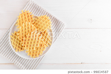 Ferratelle or pizzelle a traditional dessert or cookies from Abruzzo on a plate on a white wooden background, top view 99814587