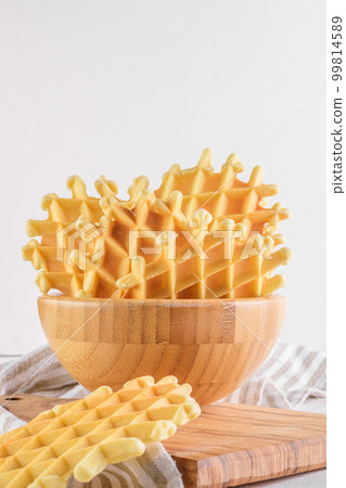 Ferratelle or pizzelle a traditional dessert or cookies from Abruzzo in a bowl on white wooden background, copy space Ferratelle or pizzelle a traditional dessert or cookies from Abruzzo in a bowl on white wooden background, copy space 99814589