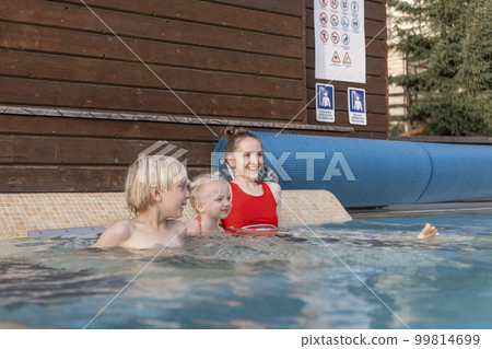 Young mother or sister and children swim in pool. Woman and two kids at outdoor swimming pool Young mother or sister and children swim in pool. Woman and two kids at outdoor swimming pool 99814699