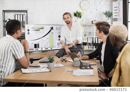 Confident man standing near big tv monitor with chart while leading conference 99815571