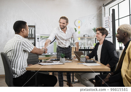 Confident bearded young businessman boss shaking hand with his young african male colleague Confident bearded young businessman boss shaking hand with his young african male colleague 99815581
