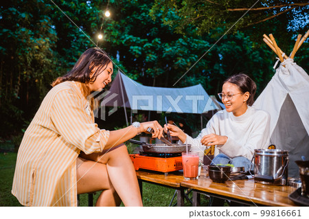 woman in orange stripped shirt cooking the beef on the grilled pan 99816661