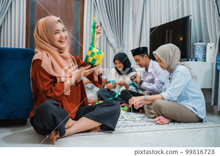 attractive veiled woman holding woven ketupat ornaments for Eid decoration 99816728