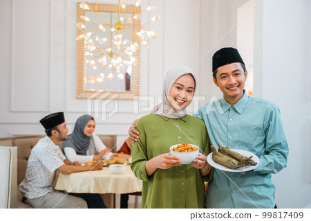 husband and wife serving food for friend and family for break fasting husband and wife serving food for friend and family for break fasting 99817409