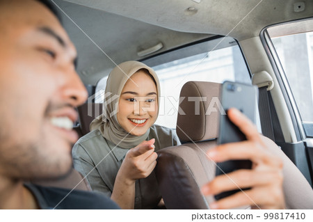 veiled female passenger asks driver about destination on phone app veiled female passenger asks driver about destination on phone app 99817410