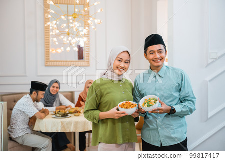 husband and wife serving food for friend and family for break fasting husband and wife serving food for friend and family for break fasting 99817417