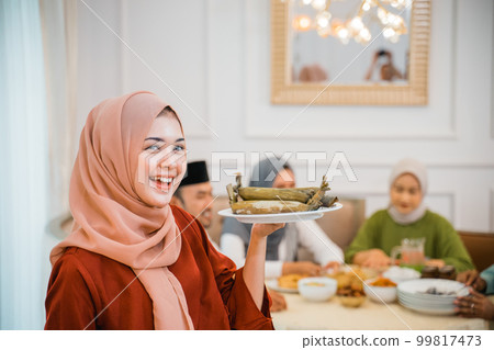 Beautiful veiled girl carrying a plate of rice cake Beautiful veiled girl carrying a plate of rice cake 99817473