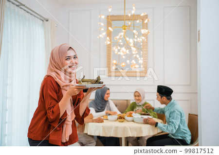 Beautiful veiled girl carrying a plate of rice cake Beautiful veiled girl carrying a plate of rice cake 99817512