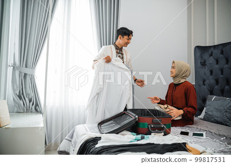 man and veiled woman chat while preparing clothes and suitcase 99817531