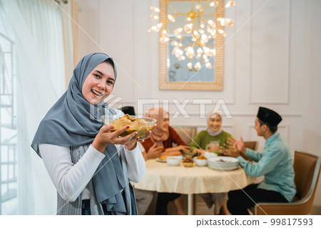 Beautiful veiled girl carrying a plate of food 99817593