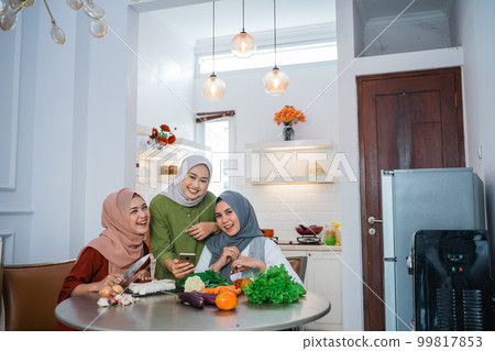 woman with hijab cooking in the kitchen while looking at internet woman with hijab cooking in the kitchen while looking at internet 99817853