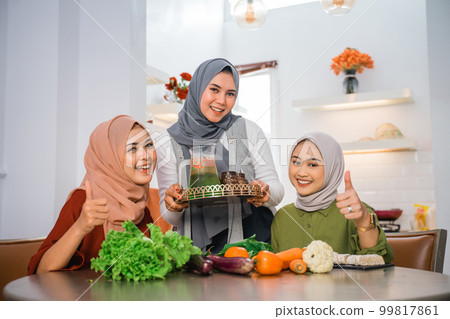 happy friend serving fresh drink for her friend in the kitchen happy friend serving fresh drink for her friend in the kitchen 99817861