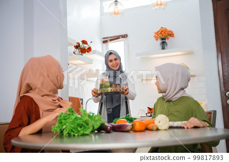 happy friend serving fresh drink for her friend in the kitchen happy friend serving fresh drink for her friend in the kitchen 99817893