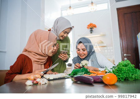 friend with hijab looking at the phone to make food 99817942