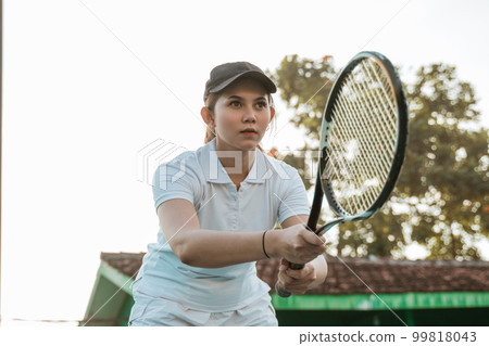 Female tennis athlete concentrating while holding a racket Female tennis athlete concentrating while holding a racket 99818043