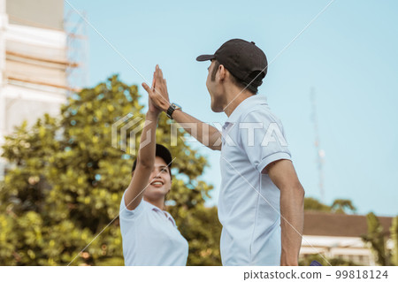 male and female tennis players give each other a high-five 99818124