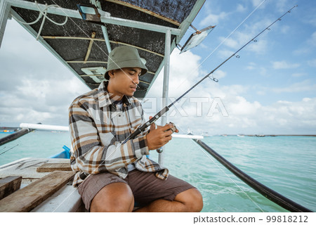 angler holding a fishing rod and checking the reel angler holding a fishing rod and checking the reel 99818212
