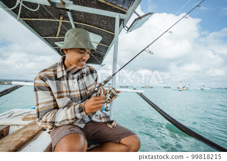 angler checking the reel before fishing with a fishing rod 99818215