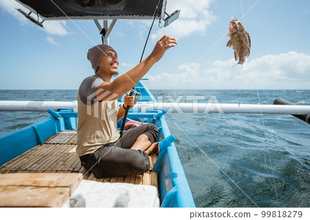 An angler is happy when he catches a fish An angler is happy when he catches a fish 99818279