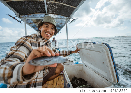smiling angler showing fish for sea fishing in a boat smiling angler showing fish for sea fishing in a boat 99818281