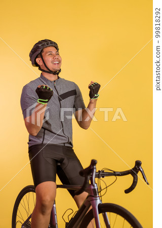 happy asian man sitting on the bicycle with clenched arms happy asian man sitting on the bicycle with clenched arms 99818292