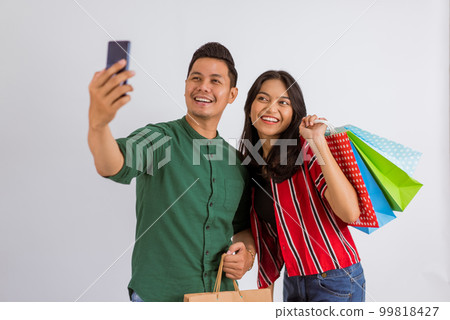 asian couple taking groufie photo while holding the shopping bags asian couple taking groufie photo while holding the shopping bags 99818427