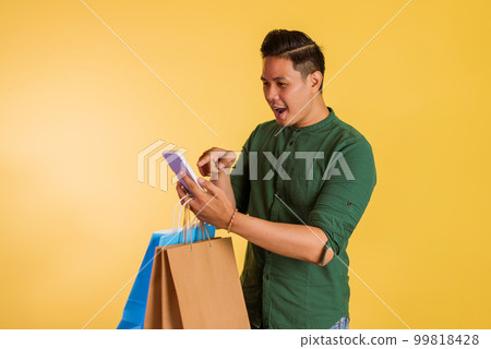 shocked asian man pointing on the phone at his hand shocked asian man pointing on the phone at his hand 99818428